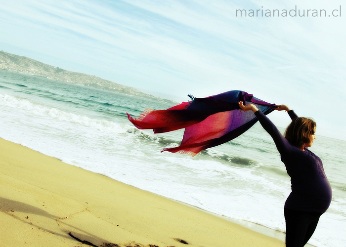 embarazada con un pañuelo al viento en la playa con el telón de fondo de Valparaíso