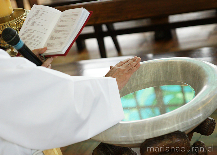 Mano de sacerdote bendiciendo pila bautismal