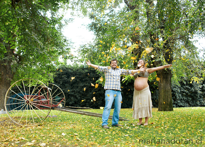 pareja de futuros padres lanzando hojas al viento
